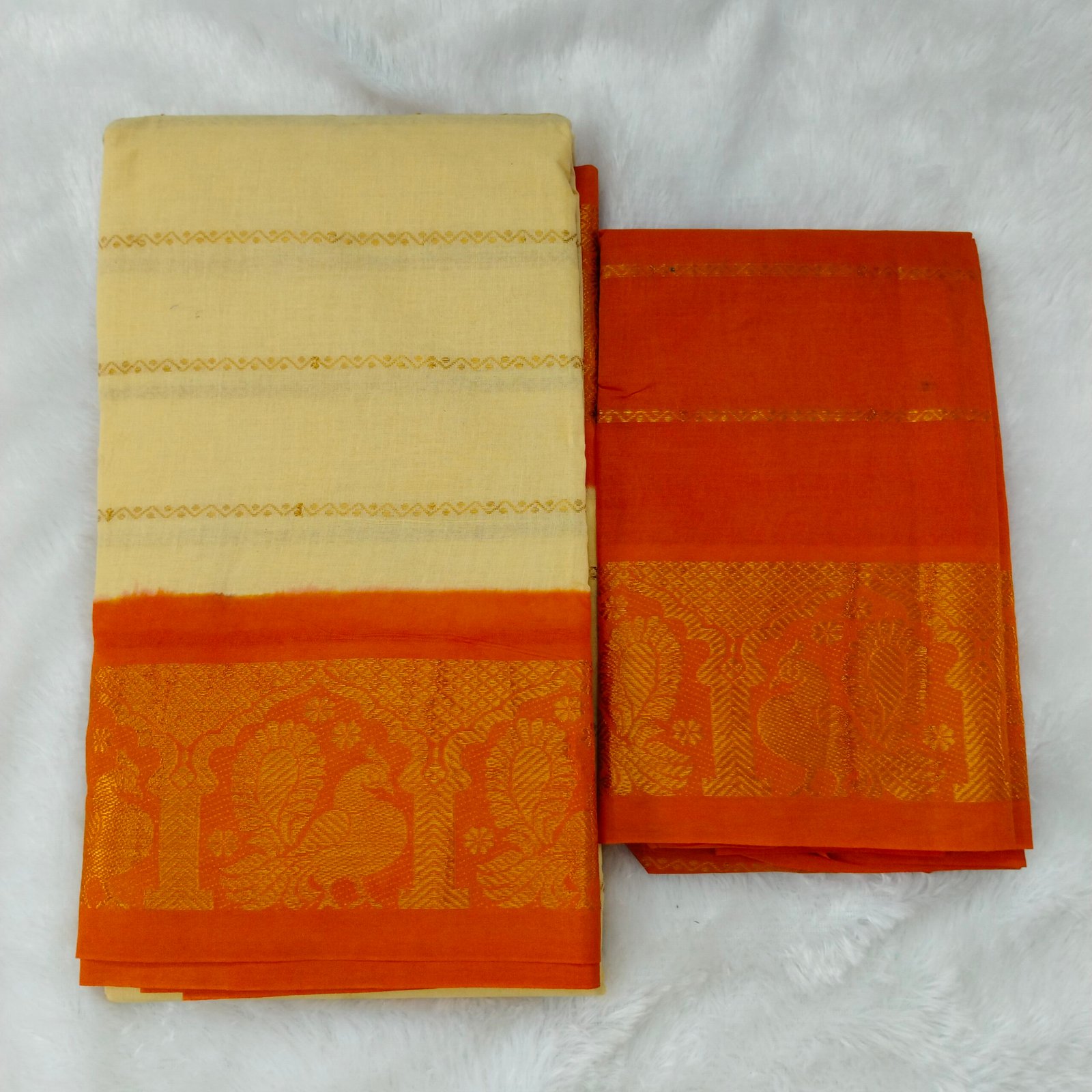 Subtle lite sandal shade contrasted with a lively orange border; traditional pallu and blouse included.