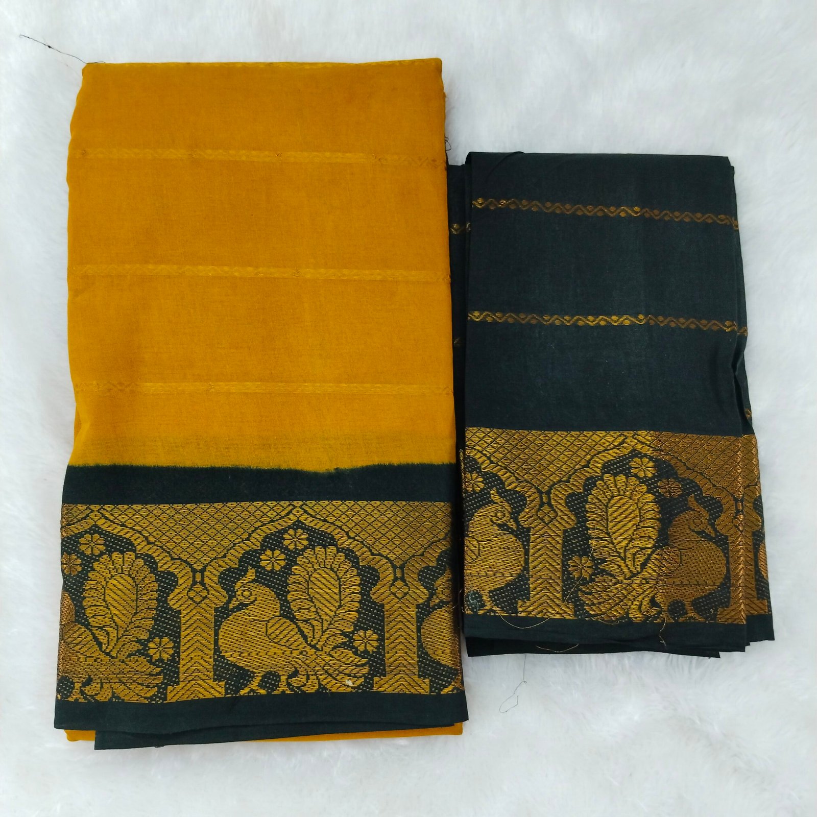 Radiant mustard yellow paired with a bold black border; contrast pallu and blouse for a classic look.